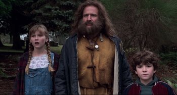 Movie still from “Jumanji” (1995), directed by Joe Johnston – A man with long hair and a beard standing next to a girl; Medium shot, Low angle