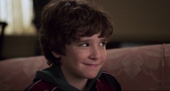Movie still from “Jumanji” (1995), directed by Joe Johnston – A young boy smiling while sitting on a couch; Close Up shot, High angle