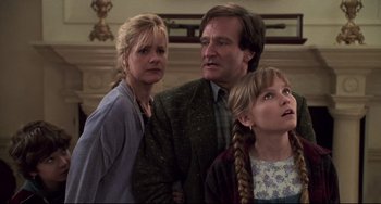 Movie still from “Jumanji” (1995), directed by Joe Johnston – A man and two women standing next to each other in a room; Medium shot, Low angle