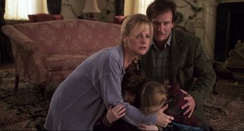 Movie still from “Jumanji” (1995), directed by Joe Johnston – A woman and a man holding a young girl in her arms; Medium shot, High angle