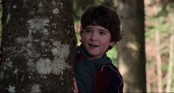 Movie still from “Jumanji” (1995), directed by Joe Johnston – A young boy leaning against a tree in the woods; Close Up shot, Low angle