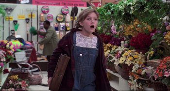 Movie still from “Jumanji” (1995), directed by Joe Johnston – A young girl in overalls is holding a piece of wood in her hand; Medium shot, Over the shoulder angle