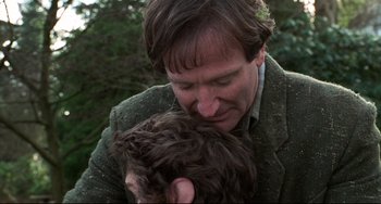 Movie still from “Jumanji” (1995), directed by Joe Johnston – A man holding a dog in his arms; Close Up shot, Over the shoulder angle