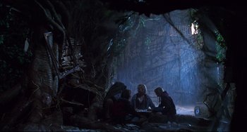 Movie still from “Jumanji” (1995), directed by Joe Johnston – A group of people sitting in a cave; Wide shot, Low angle