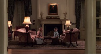 Movie still from “Jumanji” (1995), directed by Joe Johnston – Two people sitting in a living room near a fire place; Wide shot, Low angle