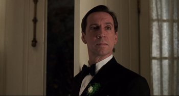 Movie still from “Jumanji” (1995), directed by Joe Johnston – A man wearing a tuxedo and a bow tie in front of a window; Close Up shot, Low angle