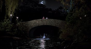 Movie still from “Jumanji” (1995), directed by Joe Johnston – Two people are sitting on a bridge over a river at night; Extreme Wide shot, High angle