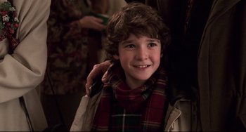 Movie still from “Jumanji” (1995), directed by Joe Johnston – A young boy wearing a scarf and smiling for the camera; Close Up shot, Over the shoulder angle
