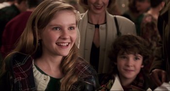 Movie still from “Jumanji” (1995), directed by Joe Johnston – A young girl smiling with two older women behind her; Close Up shot, Over the shoulder angle