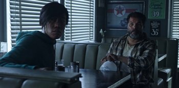 Movie still from “Black Summer” (2019), created by John Hyams – A man and a woman sitting at a table in a restaurant; Medium shot, Over the shoulder angle