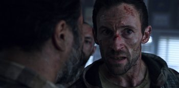 Movie still from “Black Summer” (2019), created by John Hyams – A man with a beard and a face covered in blood; Close Up shot, Over the shoulder angle