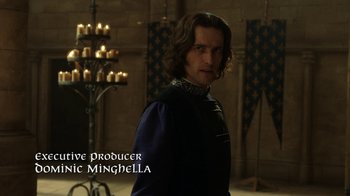 Movie still from “Knightfall” (2017), created by Richard Rayner – A man standing in front of candles in a room; Medium shot, Over the shoulder angle