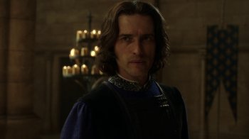 Movie still from “Knightfall” (2017), created by Richard Rayner – A person in a room with candles in the background; Close Up shot, Over the shoulder angle