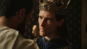 Movie still from “Knightfall” (2017), created by Richard Rayner – A person wearing a crown near another person; Close Up shot, Over the shoulder angle