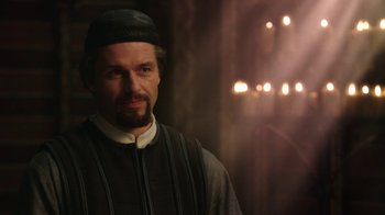 Movie still from “Knightfall” (2017), created by Richard Rayner – A man with a beard wearing a black hat; Close Up shot, Over the shoulder angle