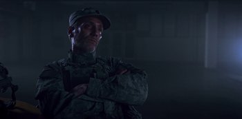 Movie still from “Black Summer” (2019), created by John Hyams – A man in fatigues standing with his arms crossed; Close Up shot, Low angle