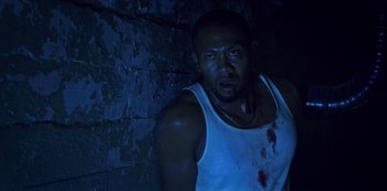 Movie still from “Black Summer” (2019), created by John Hyams – A man in a white tank top with blood on his chest; Close Up shot, Low angle