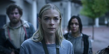 Movie still from “Black Summer” (2019), created by John Hyams – A woman with long blonde hair wearing a gray shirt; Close Up shot, Over the shoulder angle