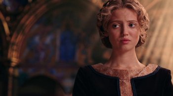 Movie still from “Knightfall” (2017), created by Richard Rayner – A woman in a black and brown dress looking at the camera; Close Up shot, Over the shoulder angle