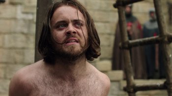 Movie still from “Knightfall” (2017), created by Richard Rayner – A man with long hair and a beard is looking at the camera; Close Up shot, Low angle