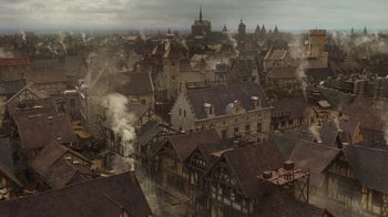 Movie still from “Knightfall” (2017), created by Richard Rayner – An aerial view of an old town with steam coming out of the chimney; Extreme Wide shot, High angle