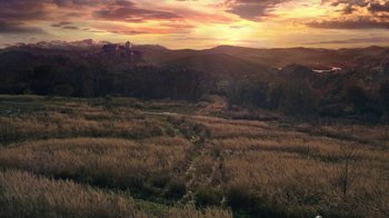 Movie still from “Knightfall” (2017), created by Richard Rayner – A view of a grassy field with mountains in the background; Extreme Wide shot, High angle