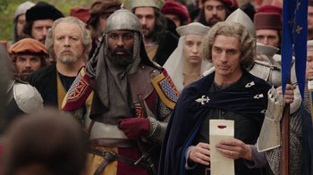 Movie still from “Knightfall” (2017), created by Richard Rayner – A group of men in medieval costumes standing next to each other; Medium shot, Over the shoulder angle