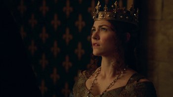 Movie still from “Knightfall” (2017), created by Richard Rayner – A woman wearing a gold crown and a necklace; Close Up shot, Low angle