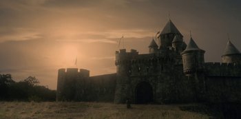 Movie still from “Knightfall” (2017), created by Richard Rayner – A castle with a person standing in front of it; Extreme Wide shot, Low angle