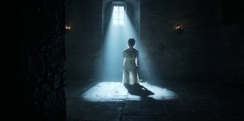 Movie still from “Knightfall” (2017), created by Richard Rayner – A woman in a white dress standing in the light of a window; Wide shot, Low angle