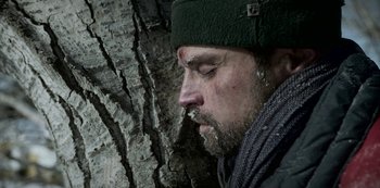 Movie still from “Black Summer” (2019), created by John Hyams – A person wearing a hat near a tree; Close Up shot, Low angle