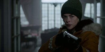 Movie still from “Black Summer” (2019), created by John Hyams – A woman in a green hat and a brown coat; Close Up shot, Over the shoulder angle