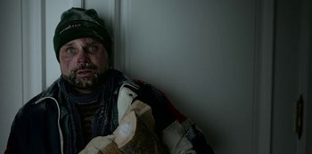 Movie still from “Black Summer” (2019), created by John Hyams – A man in a hat and jacket holding a phone; Close Up shot, Low angle