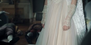 Movie still from “La Révolution” (2020), directed by Jérémie Rozan – A woman in a white dress standing in a room; Medium shot, High angle