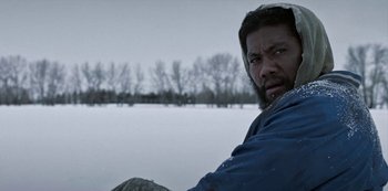 Movie still from “Black Summer” (2019), created by John Hyams – A man with a beard is sitting in the snow; Close Up shot, Over the shoulder angle