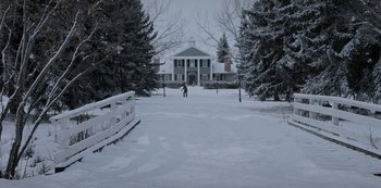 Movie still from “Black Summer” (2019), created by John Hyams – A person is walking in the snow near a house; Extreme Wide shot, Over the shoulder angle