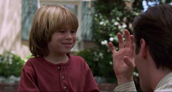Movie still from “Liar Liar” (1997), directed by Tom Shadyac – A young boy smiling and waving at a person; Close Up shot, Over the shoulder angle