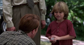 Movie still from “Liar Liar” (1997), directed by Tom Shadyac – A young boy holding something in his hand; Medium shot, Over the shoulder angle