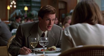 Movie still from “Liar Liar” (1997), directed by Tom Shadyac – A man sitting at a table with a plate of food and a glass of wine in front of him; Close Up shot, Over the shoulder angle