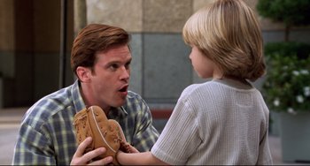 Movie still from “Liar Liar” (1997), directed by Tom Shadyac – A man holding a baseball mitt with a child holding a glove; Close Up shot, Over the shoulder angle