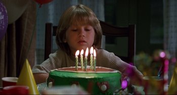 Movie still from “Liar Liar” (1997), directed by Tom Shadyac – A young child sitting in front of a birthday cake; Close Up shot, High angle