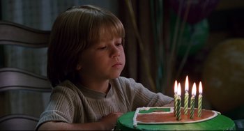 Movie still from “Liar Liar” (1997), directed by Tom Shadyac – A young boy blowing out candles on a birthday cake; Close Up shot, High angle