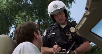 Movie still from “Liar Liar” (1997), directed by Tom Shadyac – A police officer writing a ticket for a man sitting in front of him; Close Up shot, Low angle