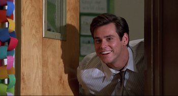 Movie still from “Liar Liar” (1997), directed by Tom Shadyac – A man in a dress shirt and tie smiling for the camera; Medium shot, Over the shoulder angle