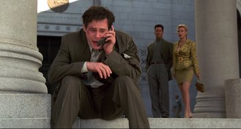 Movie still from “Liar Liar” (1997), directed by Tom Shadyac – A man sitting on the ground while talking on a cell phone; Medium shot, Low angle