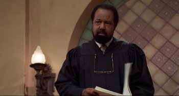 Movie still from “Liar Liar” (1997), directed by Tom Shadyac – A man wearing a robe and holding a book; Medium shot, Low angle