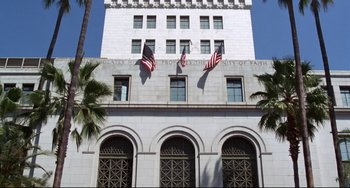 Movie still from “Liar Liar” (1997), directed by Tom Shadyac – Three american flags are flying on the side of a white building; Extreme Wide shot, Low angle