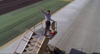 Movie still from “Liar Liar” (1997), directed by Tom Shadyac – A man standing on the stairs of an airplane; Wide shot, High angle