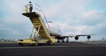 Movie still from “Liar Liar” (1997), directed by Tom Shadyac – A man standing on the stairs of an airplane on a runway; Extreme Wide shot, Low angle