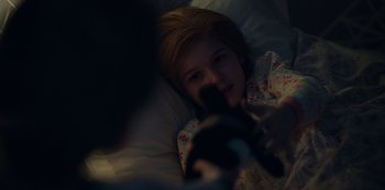Movie still from “Locke & Key” (2020), created by Carlton Cuse – A little girl laying in a bed holding a camera; Close Up shot, High angle